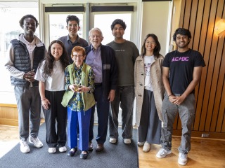 students standing with an older couple with an award 