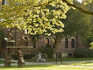 A girl walking a bicycle next to Steiner Hall