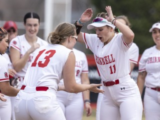 Two softball players high five while getting pumped up for the start of the game.