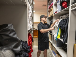 Luke Thompson putting away jerseys in the athletic closet.