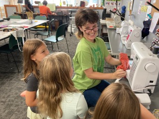 Student with 3 kids at a sewing machine
