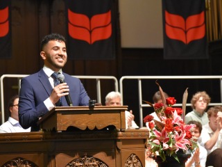 Grinnell College alum Nick El Hajj speaks at the podium for at the 2024 baccalaureate ceremony.