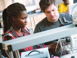 A woman and man stand near a lab equipment.