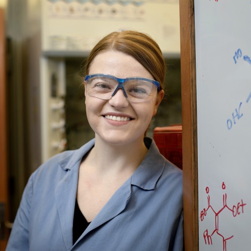 Jennifer Fulton wearing lab goggles standing by whiteboard