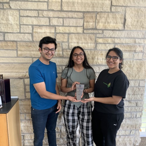 Three Grinnellians hold a trophy highlighting their case study win.