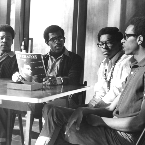A group of four young men gather around a table.