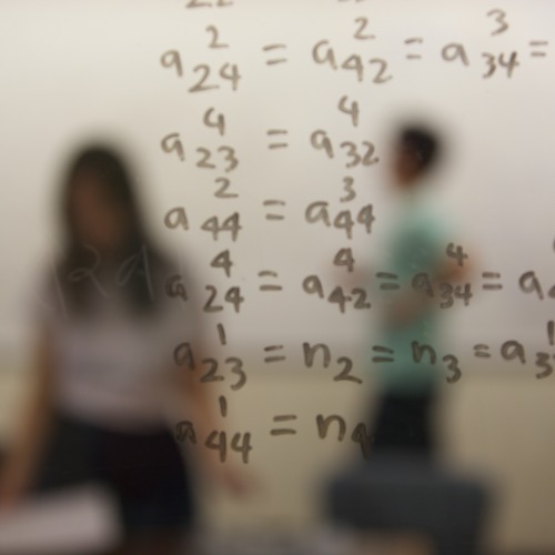 Math equations are written on a window, behind which are sillhouetes of people.