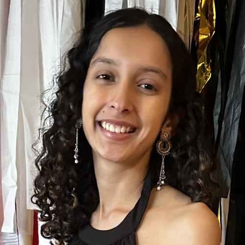 A smiling young woman poses in from of colorful flags.
