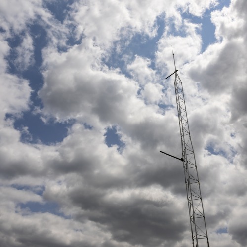 Looking up at the tower with a mix of clouds and blue sky behind it