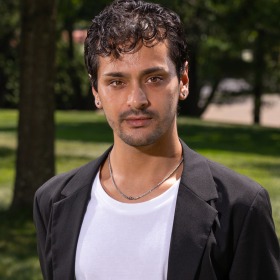 Man with short dark hair in black jacket and white undershirt