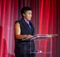 Photo of Valeriya Woodard '25 giving a speech with a deep red backdrop. 