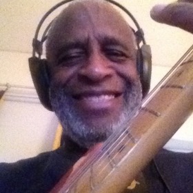 Dartanyan Brown with a guitar and headphones smiling