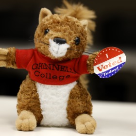 Squirrel with Grinnell College shirt holding voting sticker