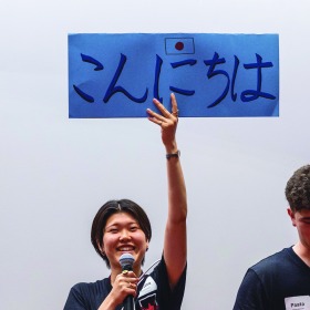 Student holding sign that says "hello" in Japanese