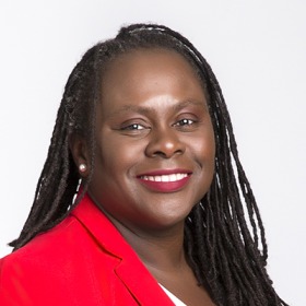 A headshot of Onwuachi-Willig wearing braids and a red blazer She smiles into the camera.