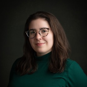 woman with long dark hair wearing dark green shirt with dark background