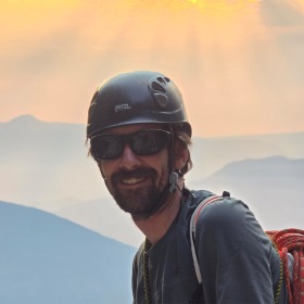 man with sunset sky behind him