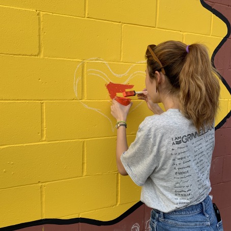 student painting heart on mural 