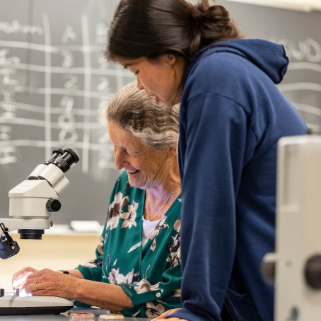Professor and student set up microscope in a science lab