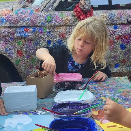 little girl working on art project with glitter truck behind