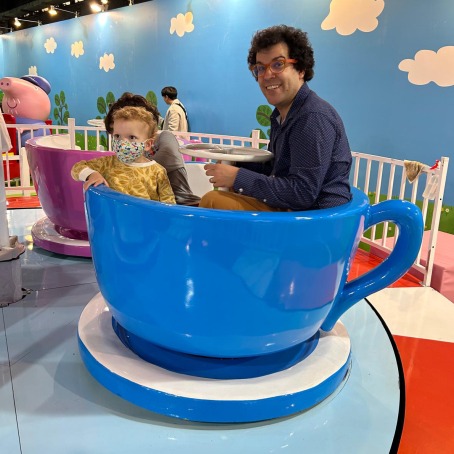 Elias Saba and his young child enjoy a teacup amusement ride