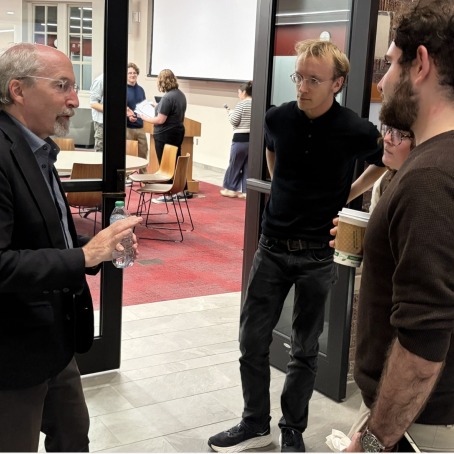 Students speak with a lecturer in a hallway