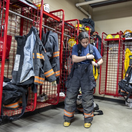 person getting in fireman gear with red lockers behind