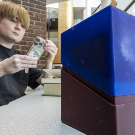 Student with phone and box of cards
