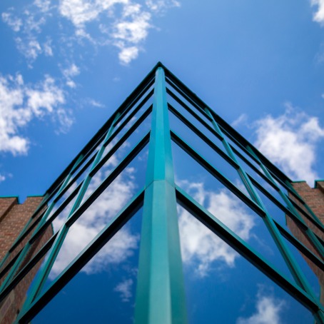 blue sky with white clouds reflecting in building windows