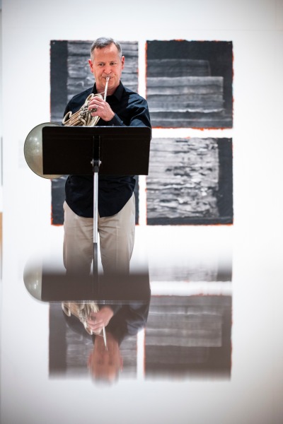 Eric McIntyre plays horn in the Faulconer Gallery