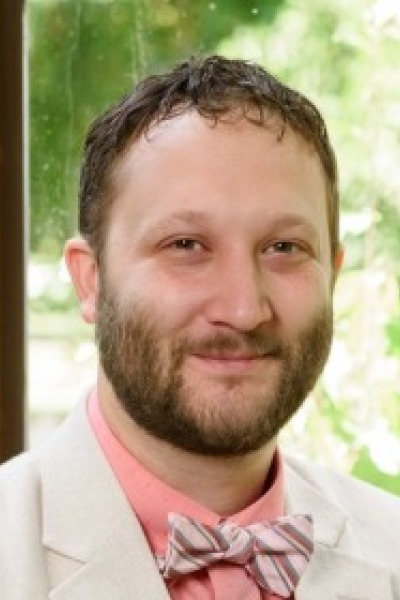 A photograph of Jonathan Wells wearing a suit jacket and pink bowtie.