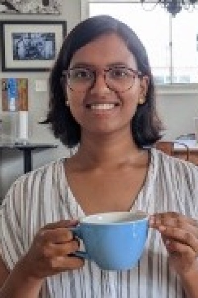 Pratima holds a blue teacup and smiles.