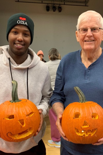 Two men holding carved pumpkins and smiling at the viewer
