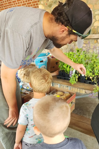 two little boys looking at plants with college student 