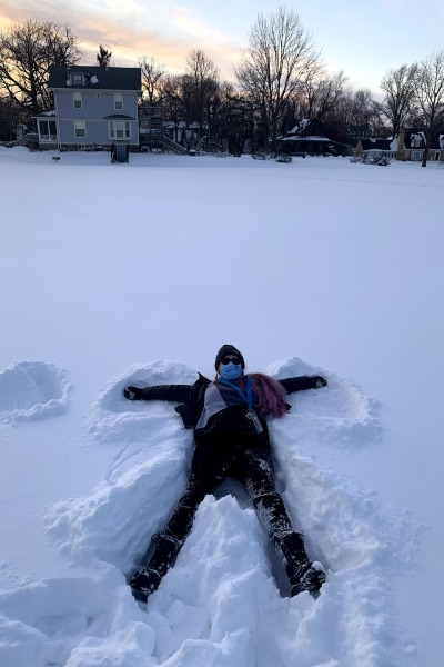 A young woman lies on the snow, making a snow angel