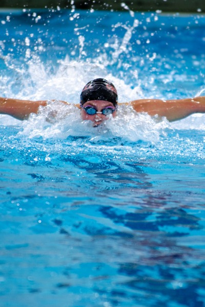 A man swimming butterfly with a black swim cap