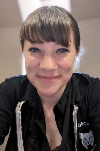 Jenny Kenkel, a woman with medium-brown hair tied behind her head and bangs wearing a black zip-front sweatshirt