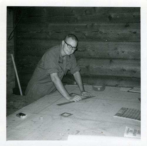 James Holbrook ’66 leaning over drawings with ruler in hand 